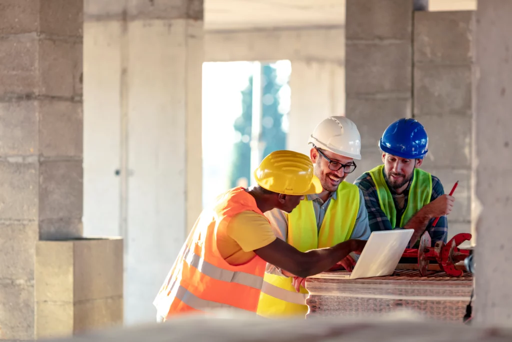 Three workers looking at a laptop on a construction site