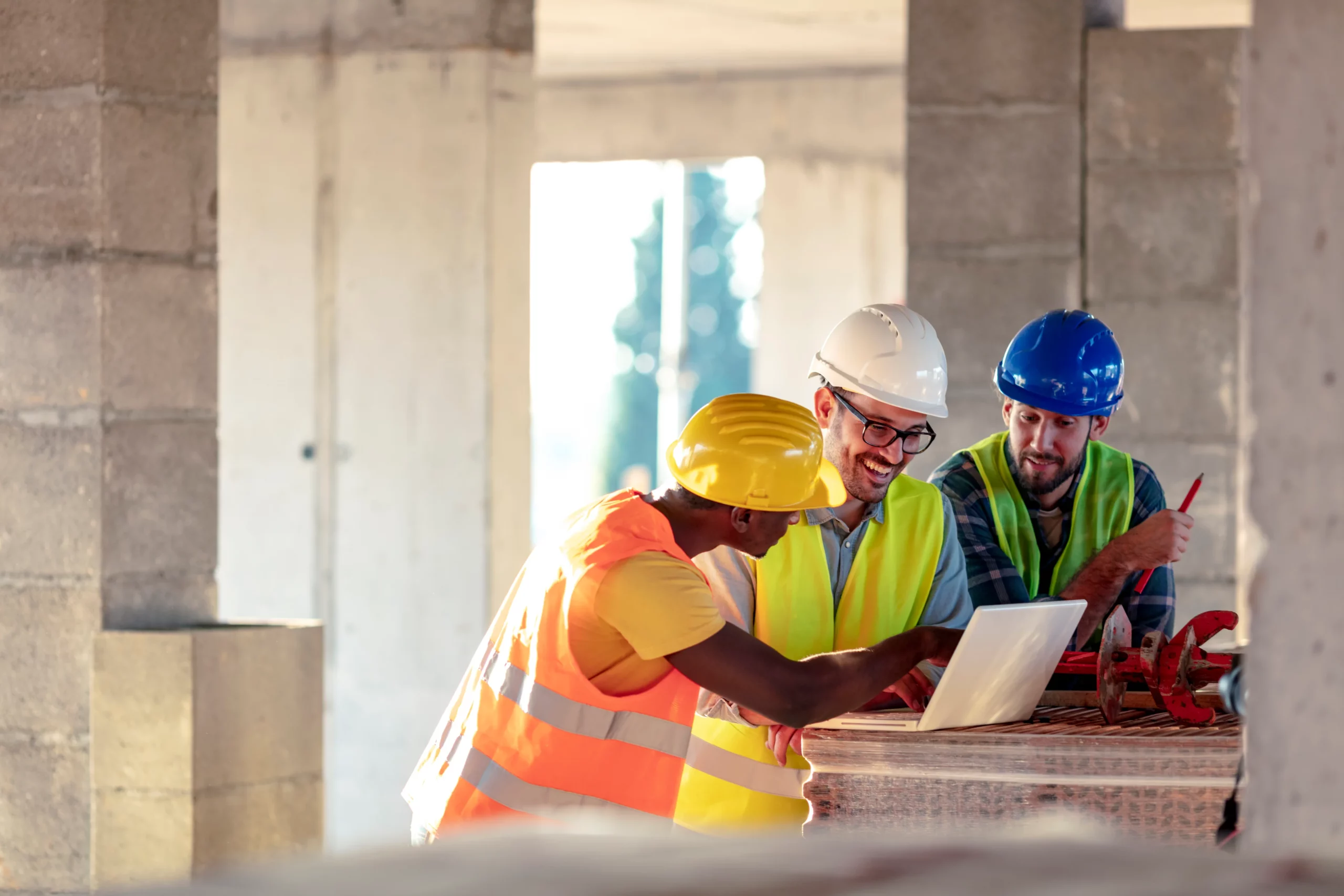 Three workers looking at a laptop on a construction site